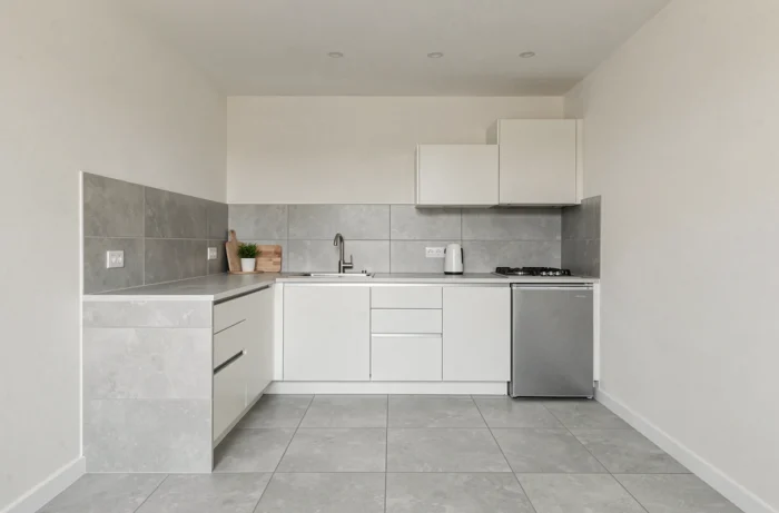 Petite cuisine avec continuité visuelle sol-mur-plafond en carrelage grand format gris clair et peinture ton sur ton créant une impression d'espace homogène