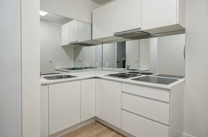 Crédence en miroir derrière la zone de cuisson dans une petite cuisine, reflétant les meubles et créant une illusion visuelle de profondeur et d'espace doublé